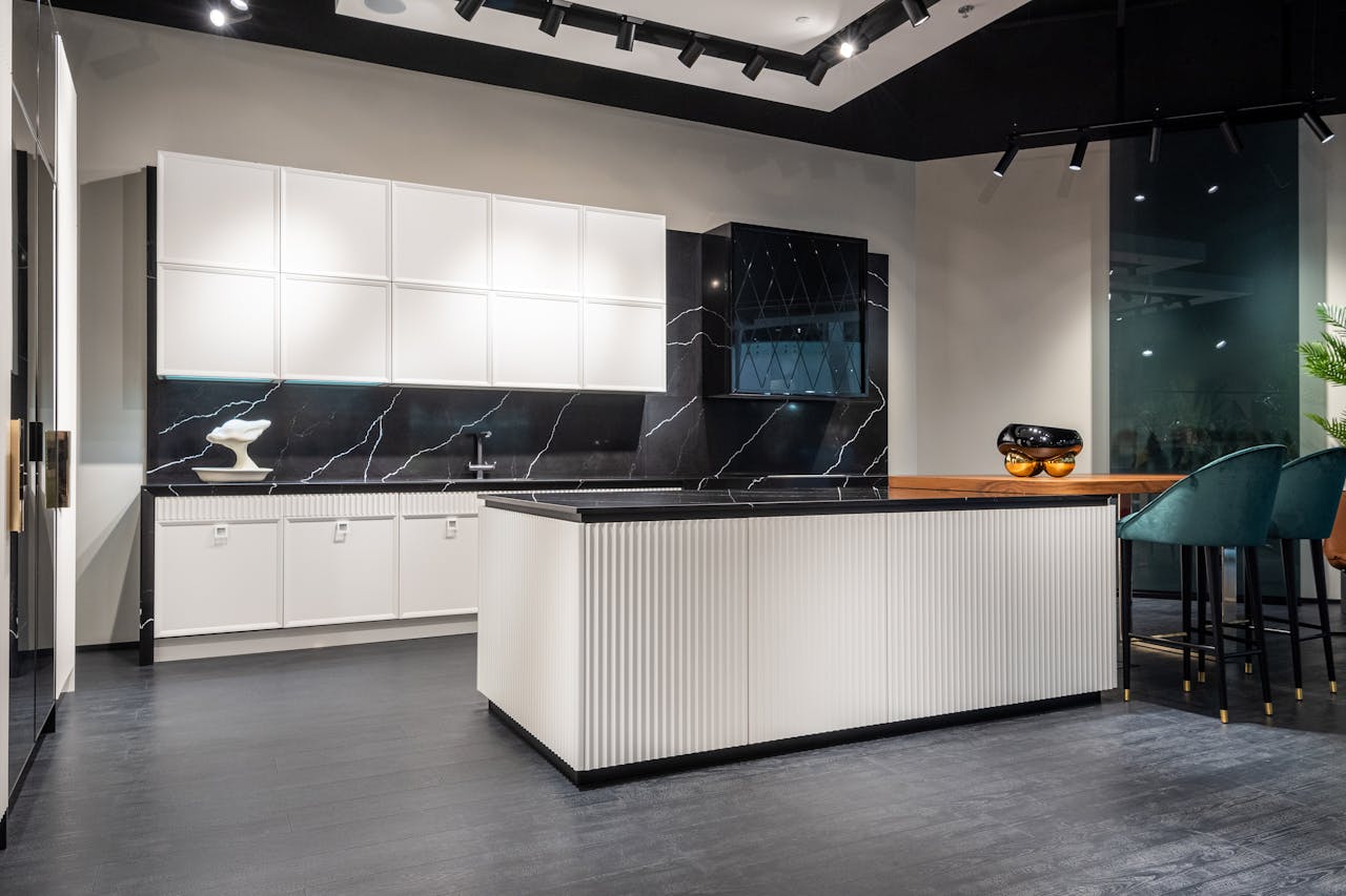 Sleek kitchen design featuring white cabinets, black countertops, and a central island in a contemporary space.